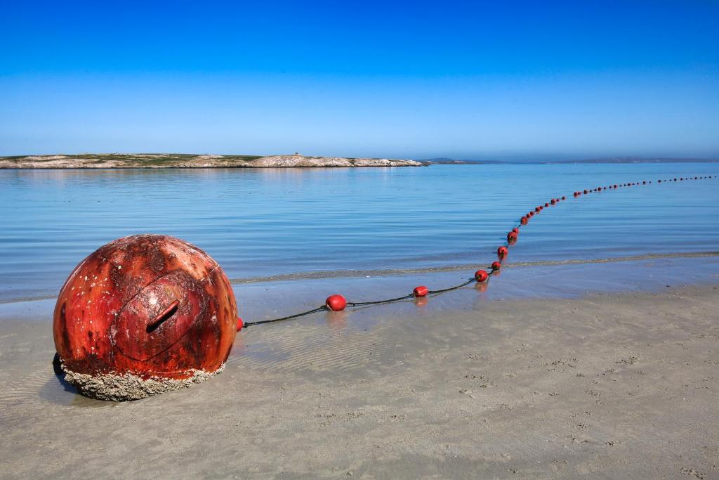 a red object on the beach next to the water at Oppi Stuppi Langebaan in Langebaan