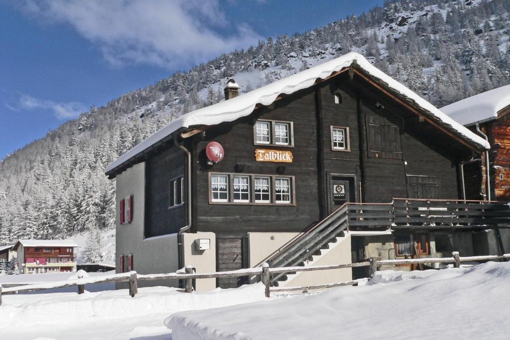 a building with snow on the roof in front of a mountain at Chalet Talblick, alte Gasse 40 in Saas-Grund