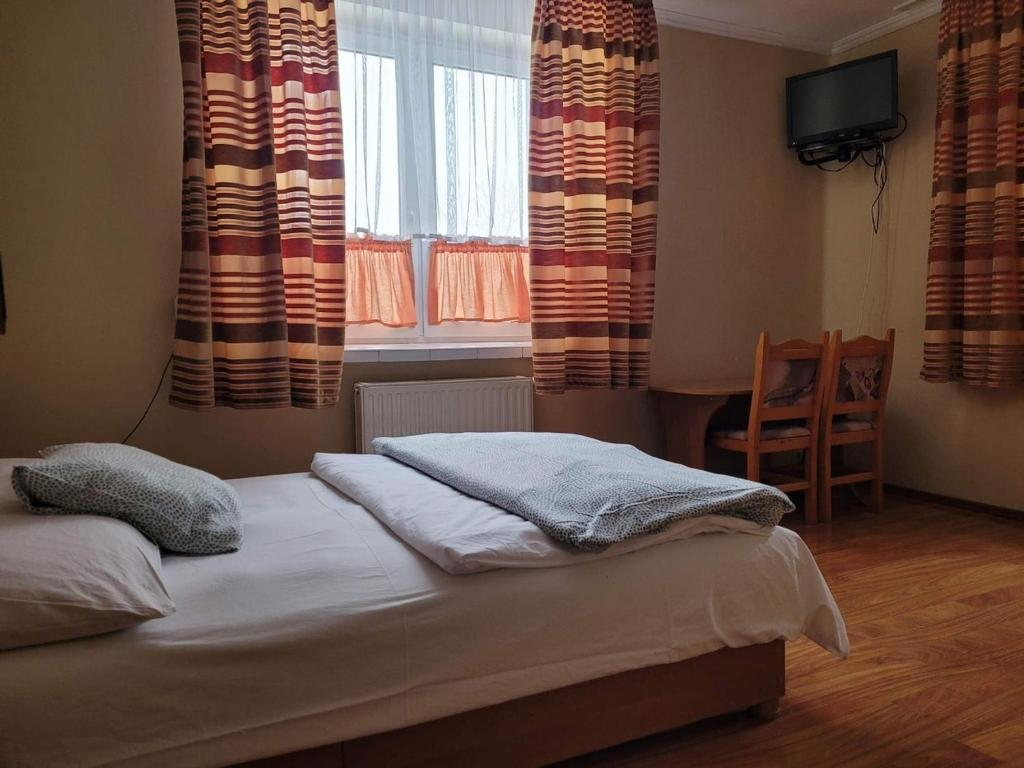 a bedroom with a bed and a window with curtains at ZAJAZD KANSAS in Konstantynów Łódzki