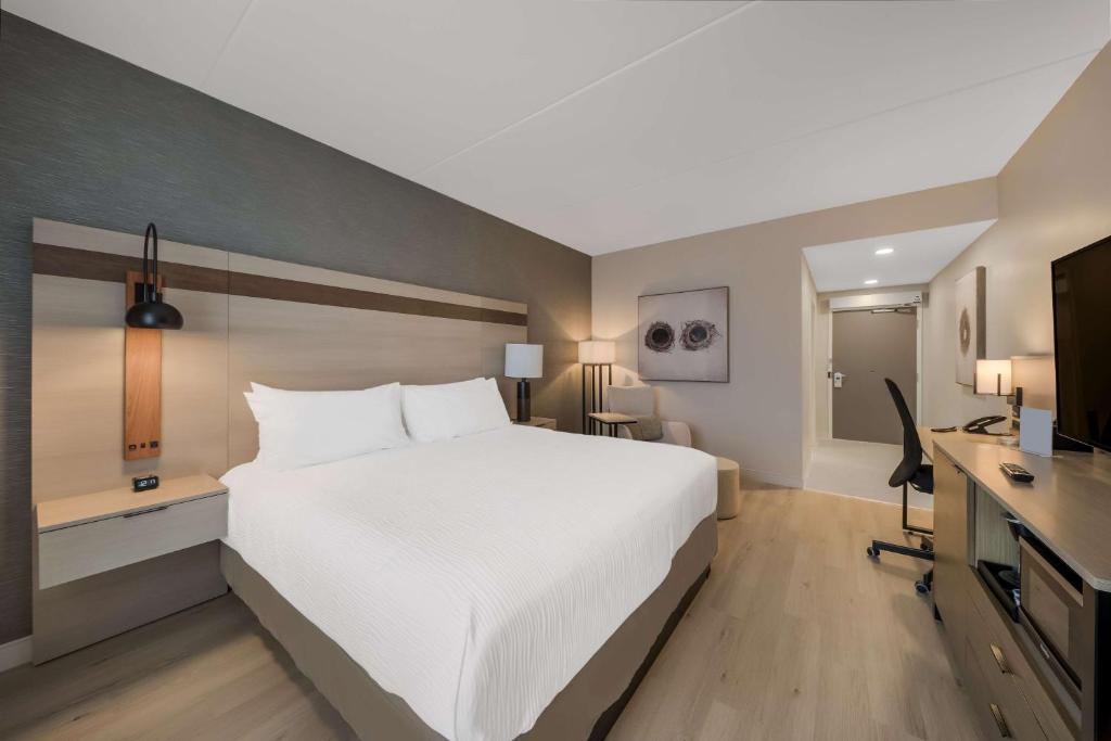 a bedroom with a large white bed and a desk at Best Western Plus Parry Sound in Parry Sound