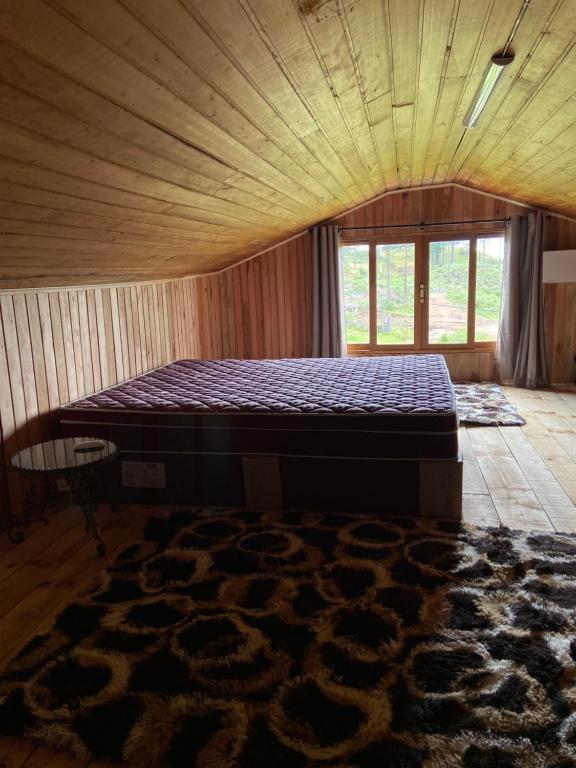 a bed in a room with a rug on the floor at Casa de campo Cantinho dos Serranos in São Joaquim