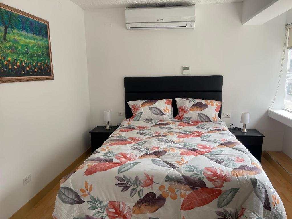a bedroom with a bed with a floral bedspread at 14 Departamento acogedor y nuevo en Miraflores in Lima