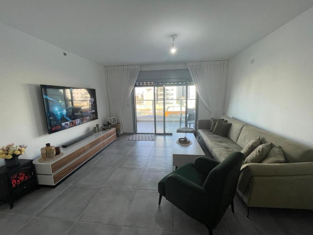 a living room with a couch and a flat screen tv at Luxury boutique apartment with balcony and sea view 3BR in Tirat Karmel