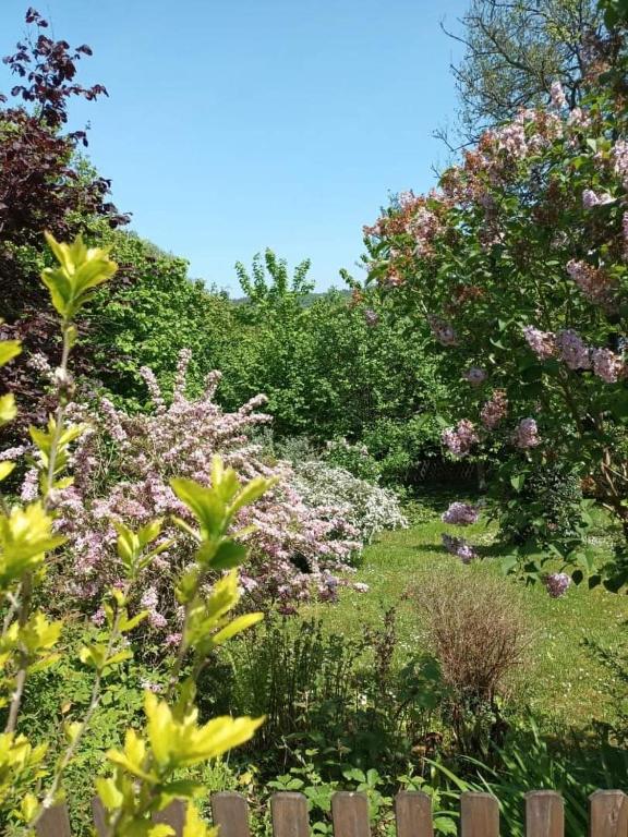 un jardin de fleurs et d'arbres avec une clôture en bois dans l'établissement L'escale Arquaise, la maison au jardin fleuri à 5 min de dieppe, à Arques-la-Bataille