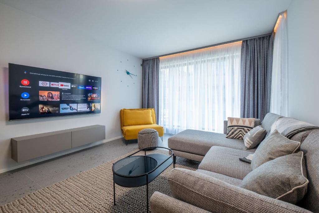 a living room with a couch and a tv at Emirates Lux Apartment and Parking in Sofia