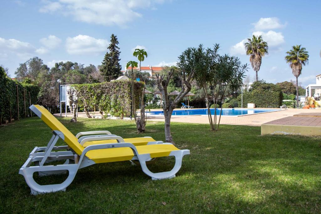 a yellow and white lounge chair in the grass near a pool at Oura 7 in Albufeira