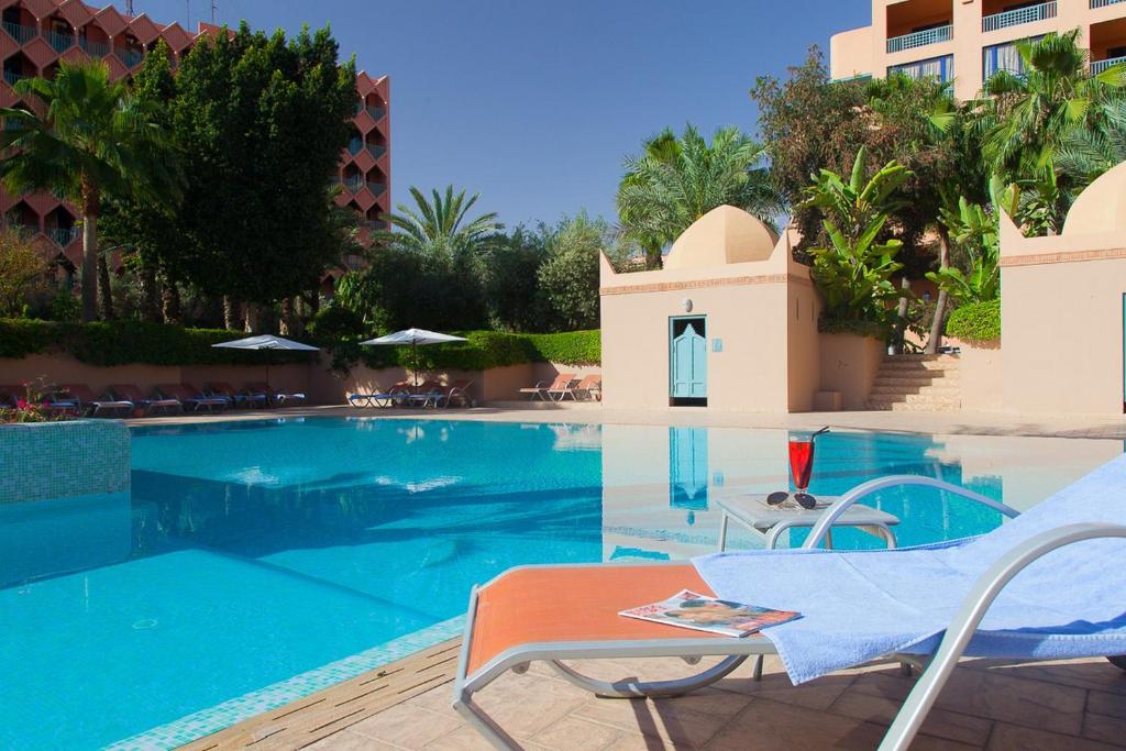 a swimming pool with a blue chair in front of it at Atlas Medina & Spa in Marrakesh