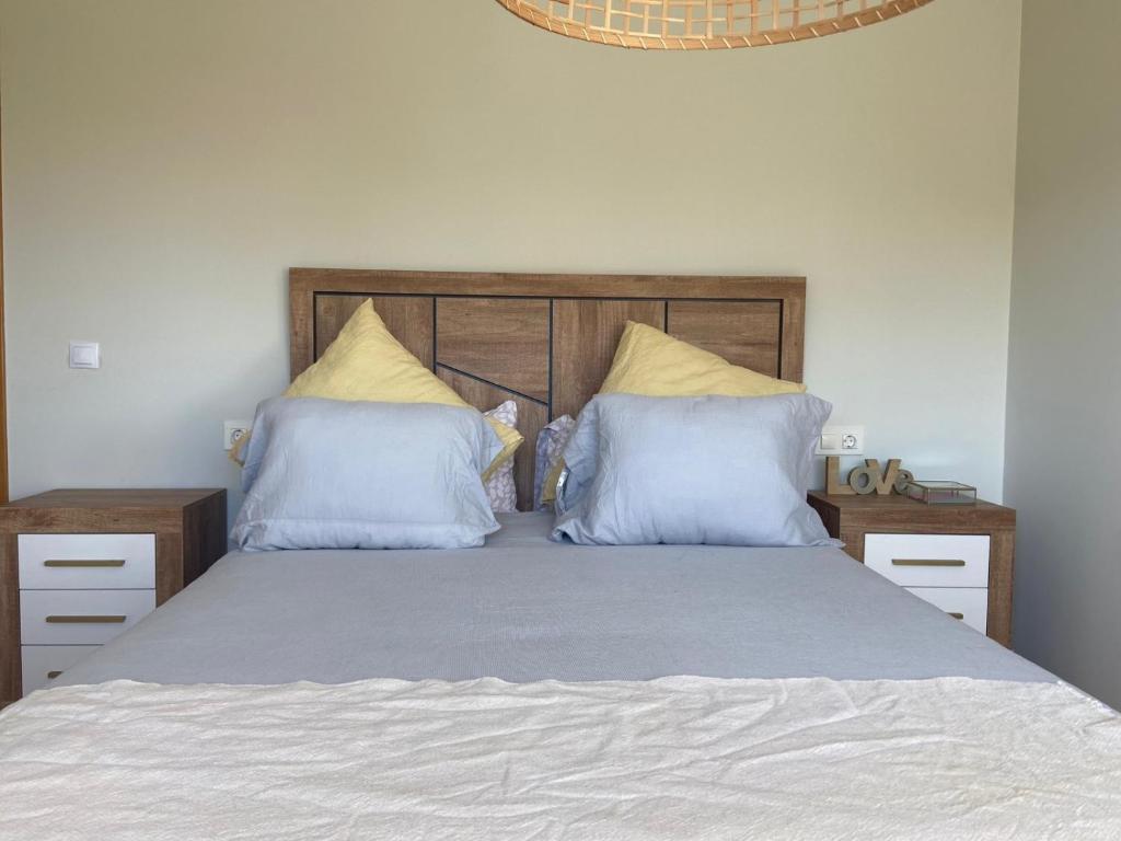 1 dormitorio con 1 cama con almohadas azules y amarillas en Ático nuevo en Arteixo con plaza de garaje, en Arteixo