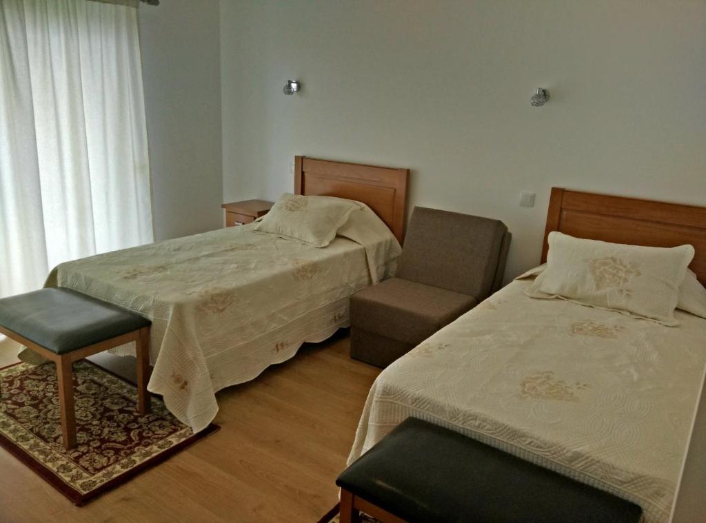 a hotel room with two beds and a chair at Agroturismo A Fidalga in Linhares