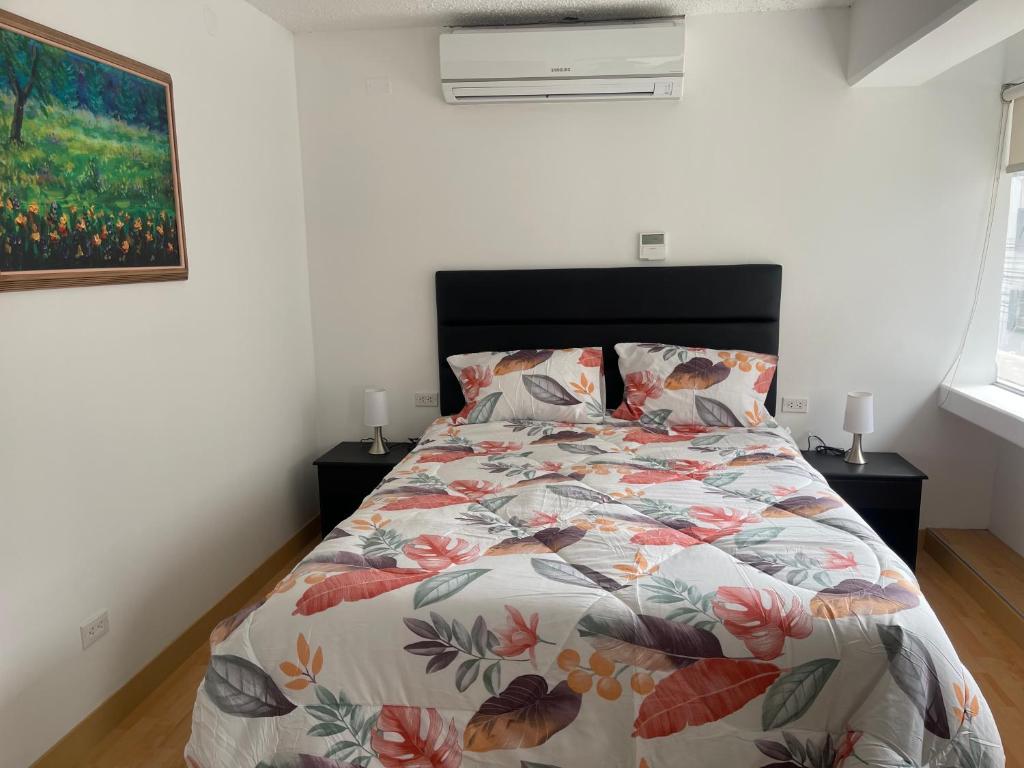 une chambre avec un lit avec un couvre-lit fleuri dans l'établissement (12) Depto con inmejorable ubicación Miraflores, à Lima