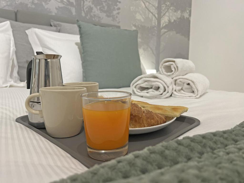un vassoio di succo d'arancia e pane su un letto di Happy Family Apartments Rovere a Genova