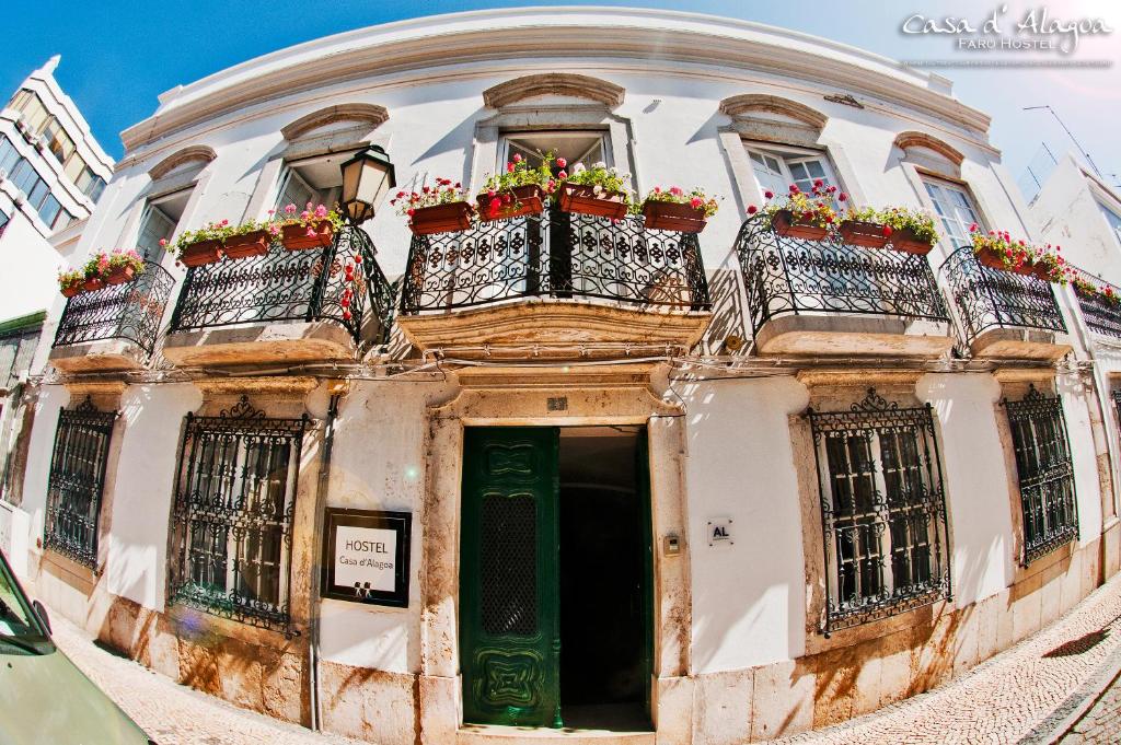 un vecchio edificio con due balconi fioriti di Hostel Casa d'Alagoa a Faro