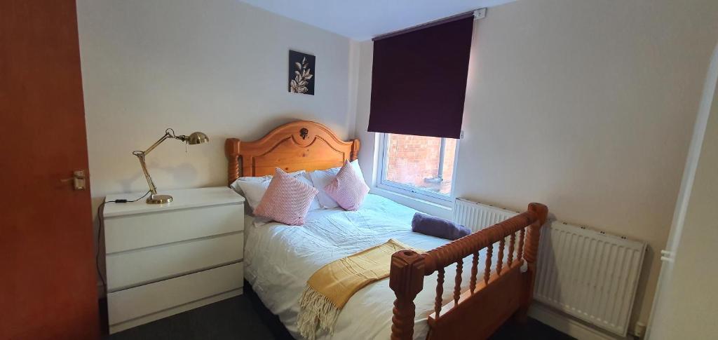 a bedroom with a bed with a wooden headboard and a window at Coventry City House in Parkside