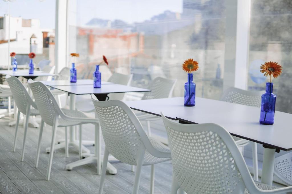 a row of tables and chairs with blue vases at Mamma Mia Hotel Boutique - Only Adults in Tossa de Mar
