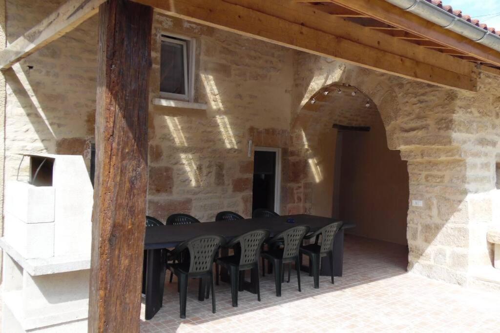 einen schwarzen Tisch und Stühle in einem Steingebäude in der Unterkunft Gîte Le Rouge Queue 3 étoiles in Fresnes