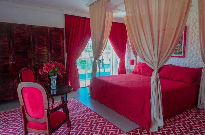 Un dormitorio con una cama y una mesa con un jarrón de flores en Relais de Charme Boutique Hotel Pititinga, en Rio do Fogo