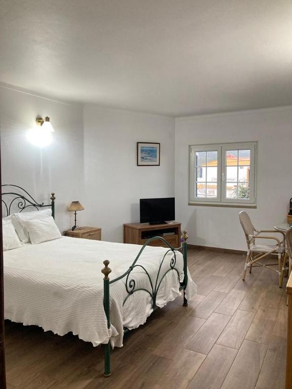 a bedroom with a bed and a desk and a television at Casa da Nazaré in Portinho da Arrábida