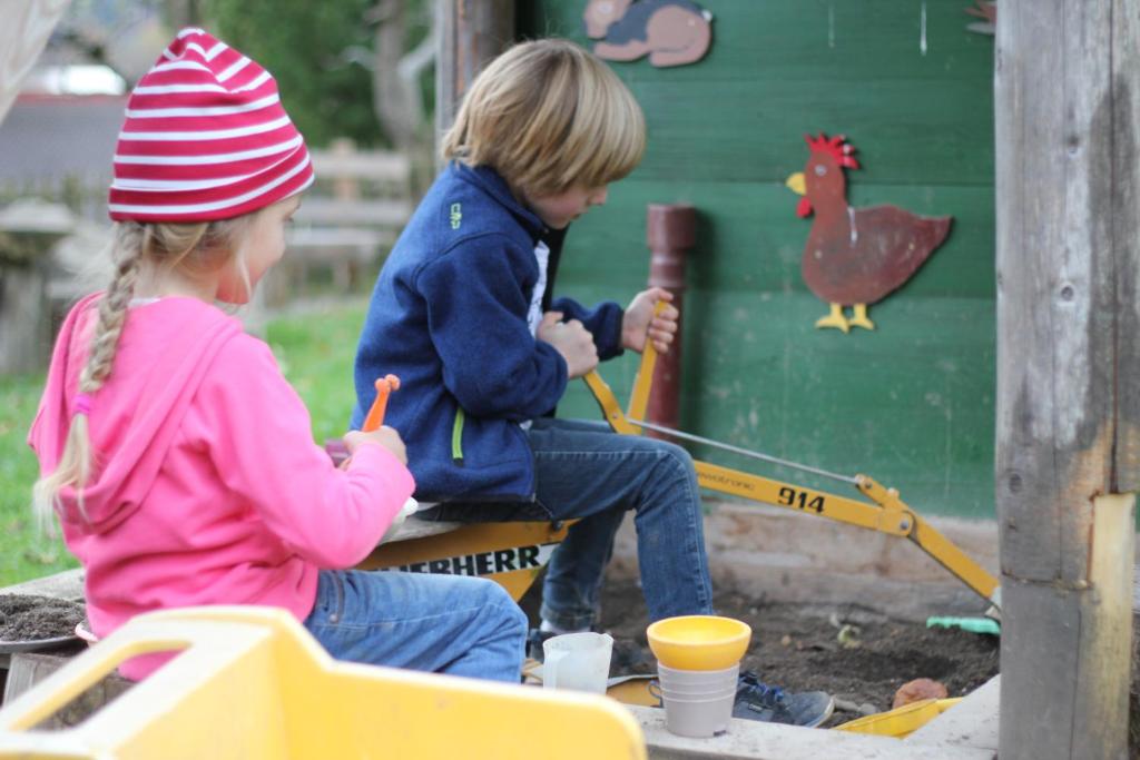 two children playing in a sandbox with a toy chicken at Bio Ferienbauernhof Greber in Schwarzenberg
