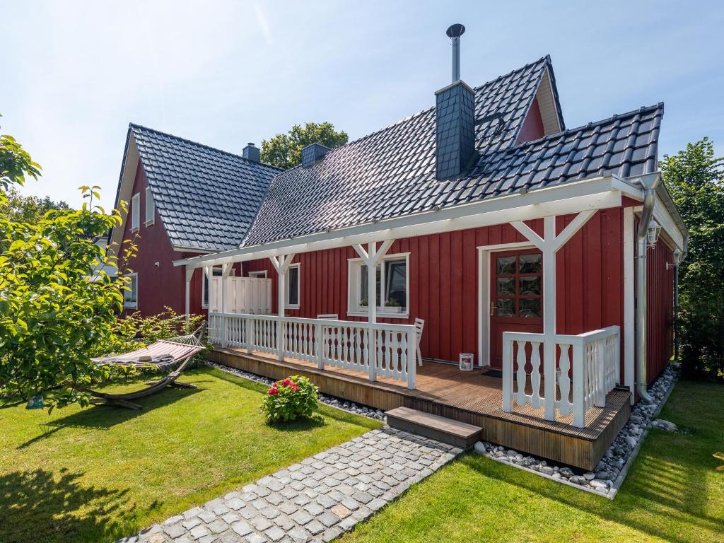 ein rotes Haus mit einer Terrasse und einem Hof in der Unterkunft Ferienwohnung Ostseestrand Zingst in Zingst