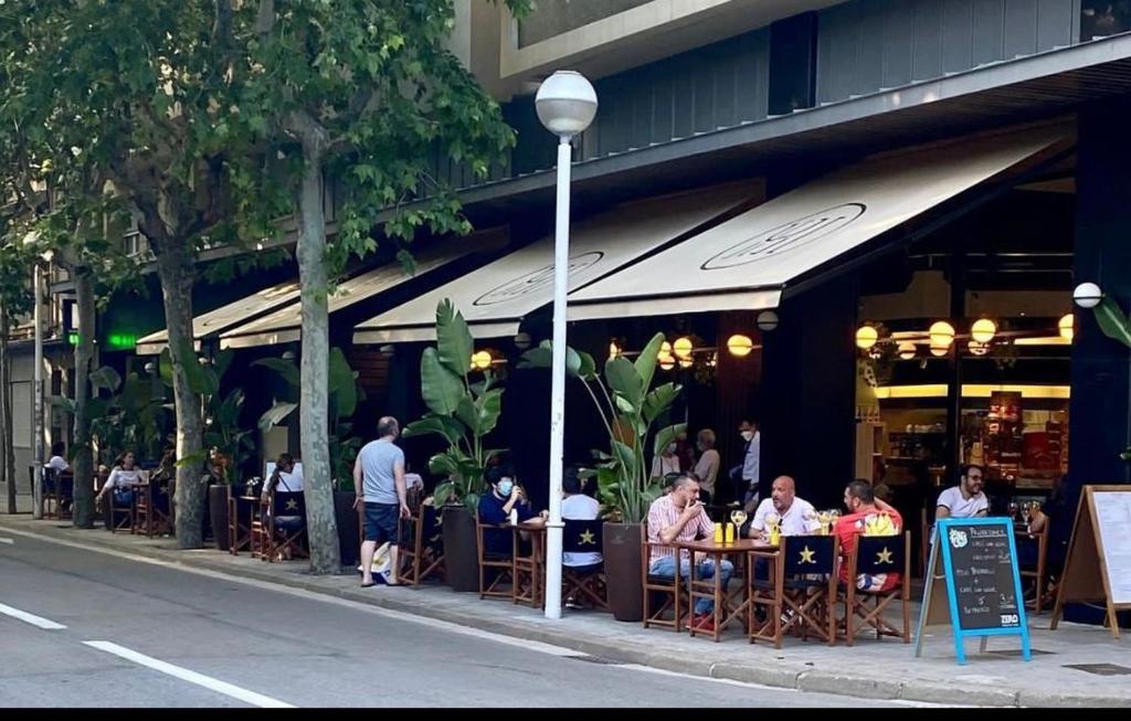 un groupe de personnes assises à des tables à l'extérieur d'un restaurant dans l'établissement Hotel Urpí, à Sabadell