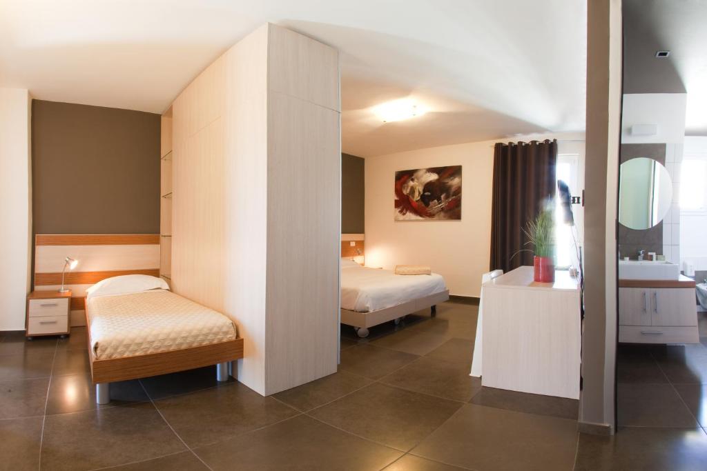 Habitación de hotel con 2 camas y espejo en Ragusa Inn, en Ragusa