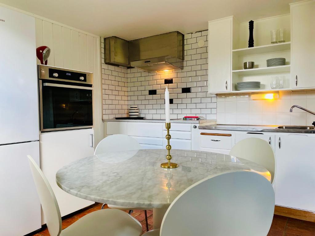 a white kitchen with a table and chairs in it at Casa Korallen in Varberg
