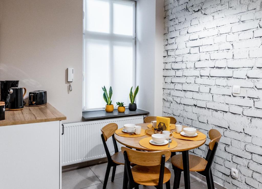 una cucina con tavolo, sedie e muro di mattoni di BeeApartments Długosza 11 a Nowy Sącz