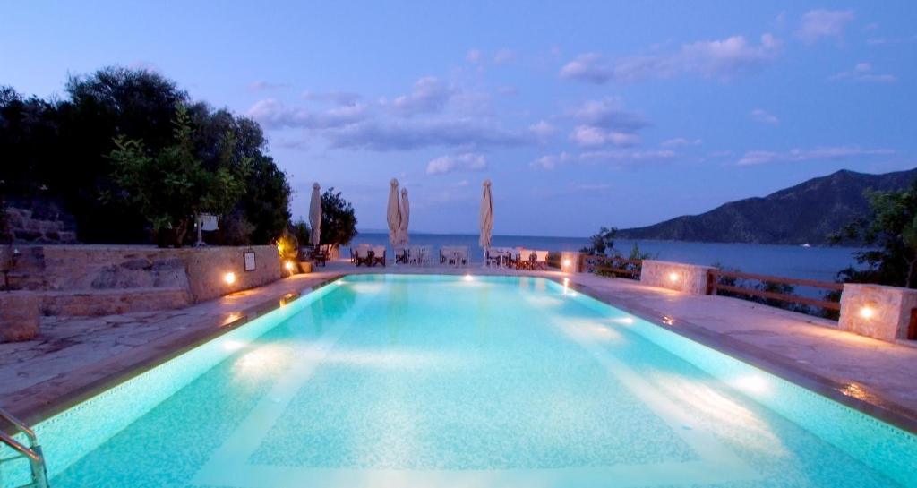 a swimming pool with a view of the ocean at night at Smyros Resort in Poulithra