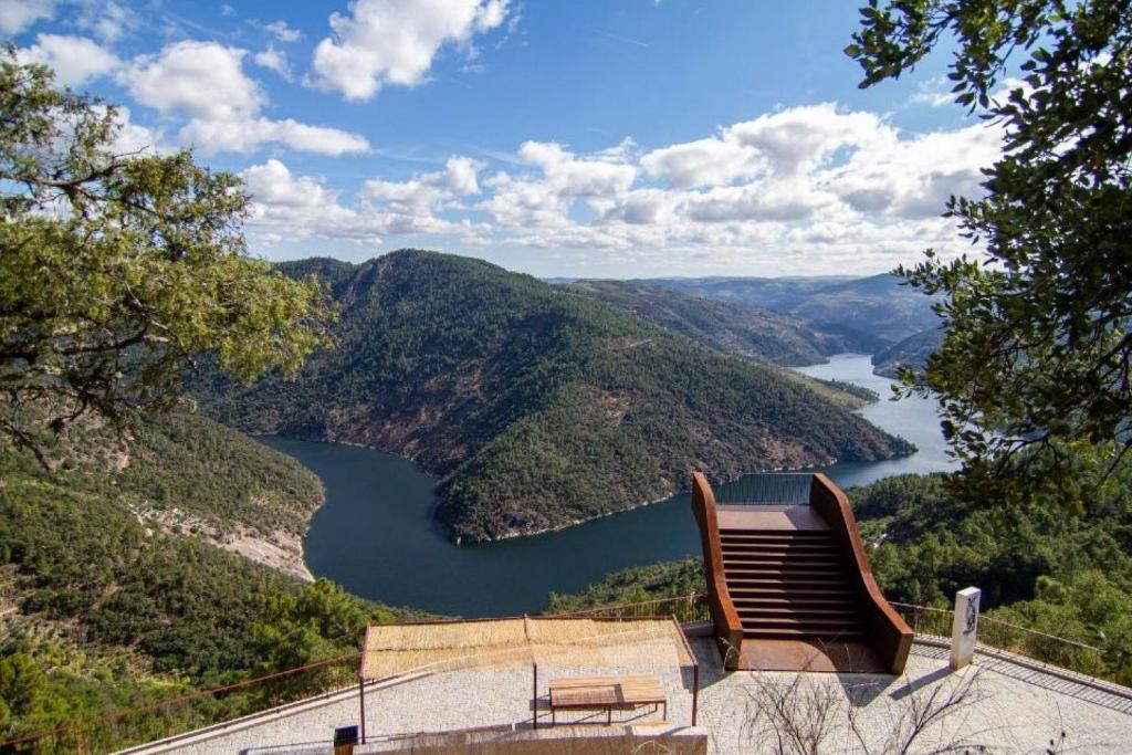 un banc installé sur le côté d'un bâtiment donnant sur un lac dans l'établissement ApartDouro, à Alijó