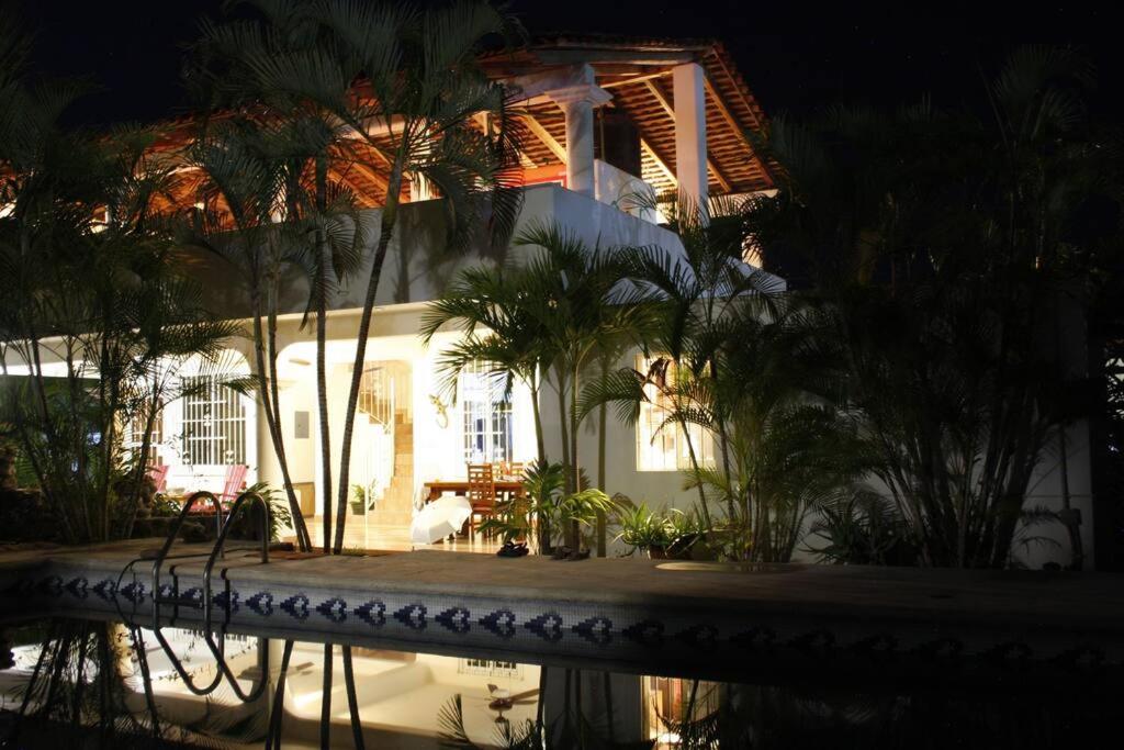 a building with palm trees and a pool at night at Lush Garden House near beaches with private pool. in Puerto Escondido