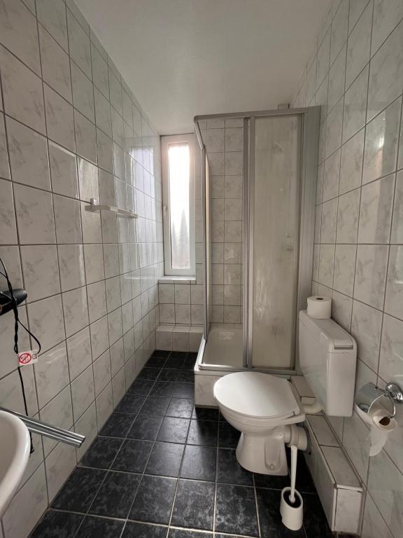 a bathroom with a toilet and a shower and a sink at Hotel Breuer in Hamm