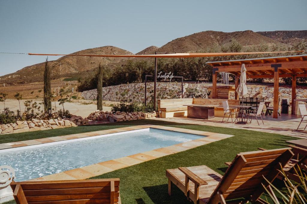 a swimming pool in a yard with a table and chairs at Finca el Mirador in Valle de Guadalupe