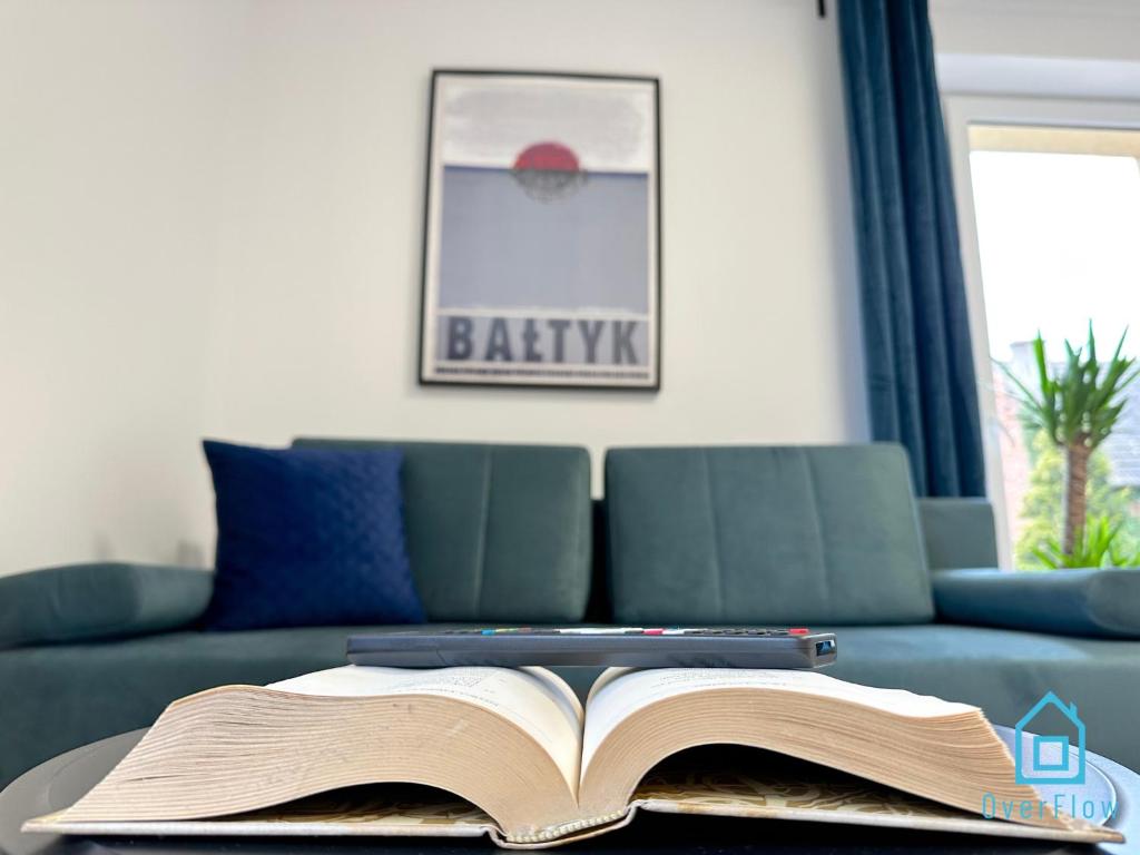an open book on a table in front of a couch at Bałtyk Apartment in Borkowo