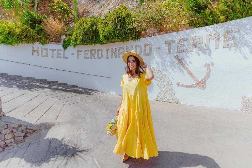 a woman in a yellow dress standing in front of a sign at Hotel Ferdinando Beach & Thermal Spa in Ischia