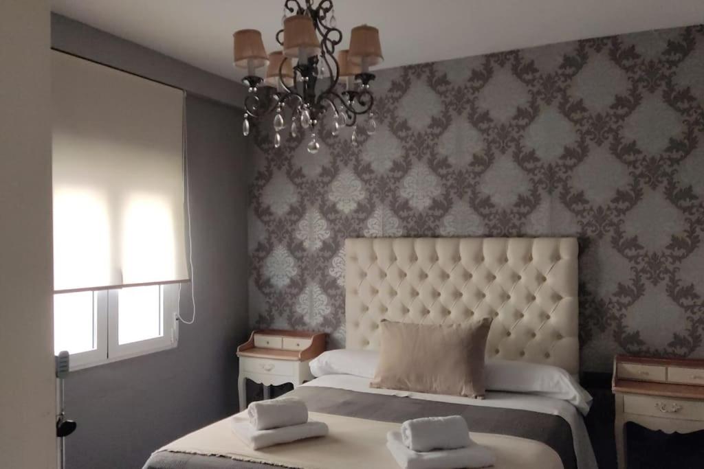 a bedroom with a bed and a chandelier at Alojamiento Marmar in Úbeda