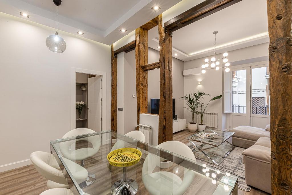 sala de estar con mesa de cristal y sillas blancas en BNBHolder Living LA LATINA, en Madrid