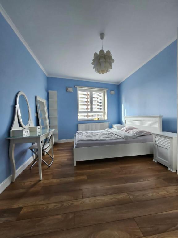 sypialnia z niebieskimi ścianami, łóżkiem i biurkiem w obiekcie Apartament Katowice Park Śląski w mieście Katowice