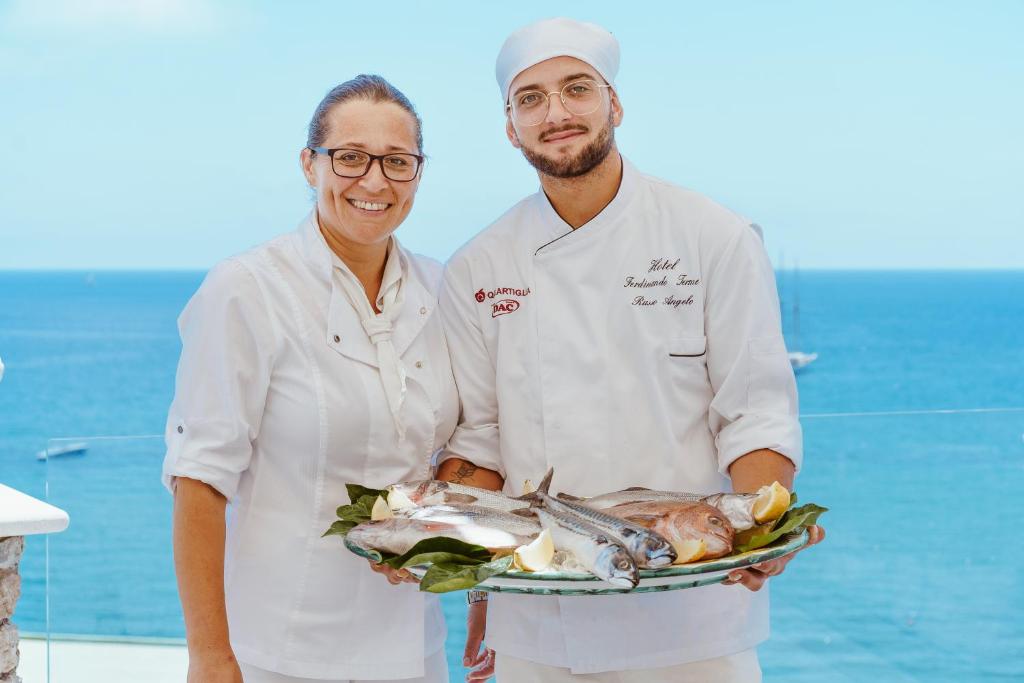 a man and a woman holding a plate of fish at Hotel Ferdinando Beach & Thermal Spa in Ischia