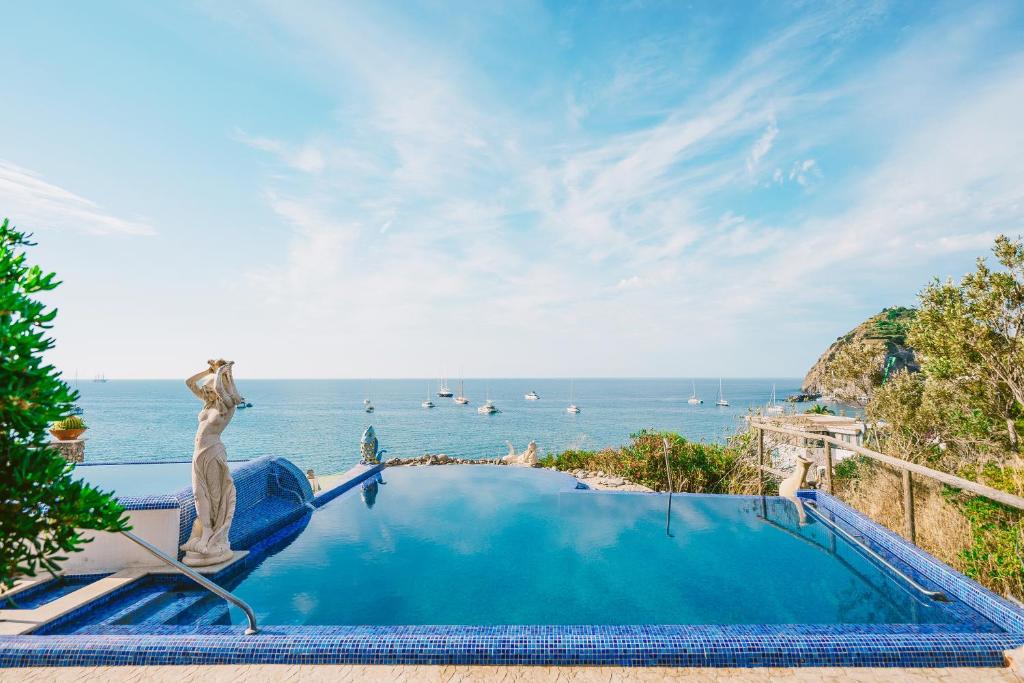 a pool with a statue next to the ocean at Hotel Ferdinando Beach & Thermal Spa in Ischia