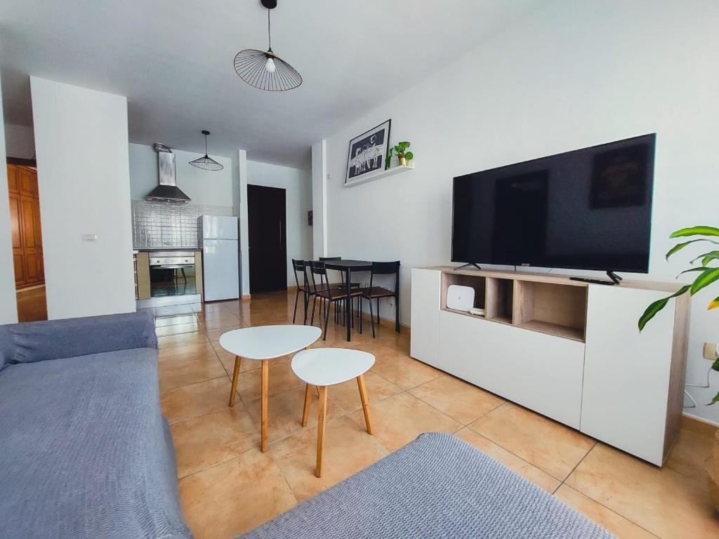 uma sala de estar com uma televisão e uma mesa e cadeiras em Acogedor apartamento Besos de Elah em San Bartolomé