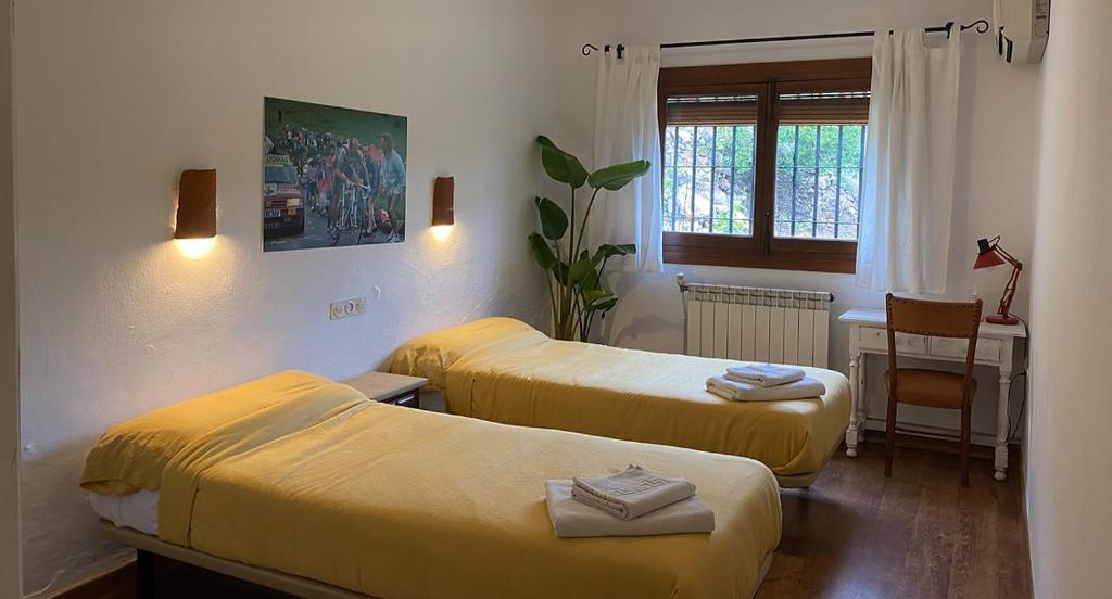 a room with two beds and a table and a window at La Ventera - summer hotel in Gualchos