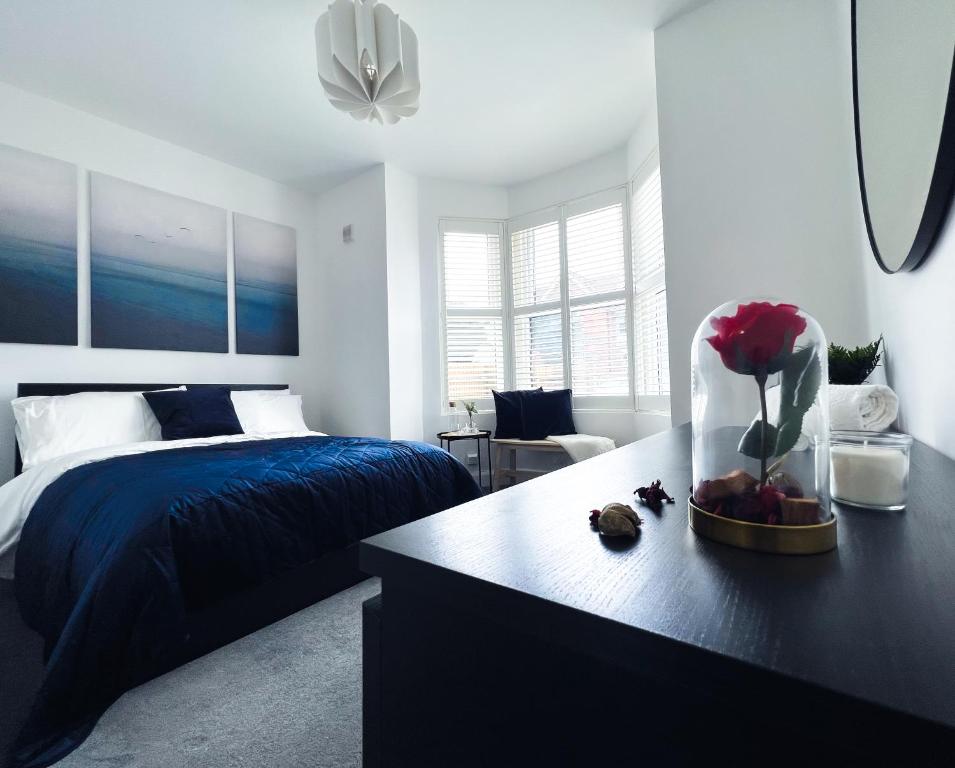 a bedroom with a bed and a table with a vase of flowers at Stylish 3 bed flat with Garden in London