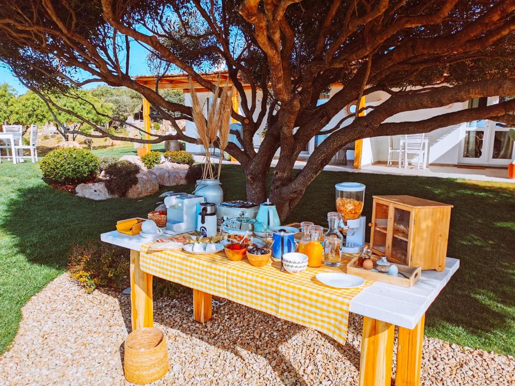 uma mesa de piquenique com comida debaixo de uma árvore em B&B Anastasia em Santa Teresa Gallura