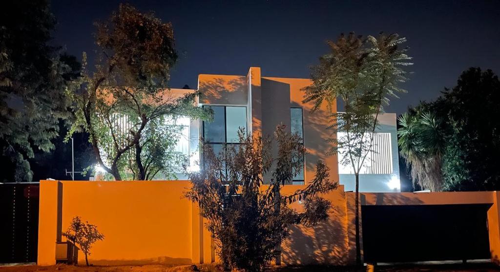 ein Haus mit orangefarbener Wand und Bäumen in der Nacht in der Unterkunft Stay In Carlazo - Unlimited WiFi, Solar backup in Roodepoort