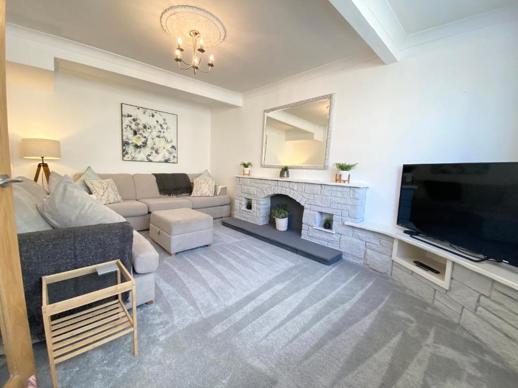 a living room with a couch and a tv and a fireplace at Modern 4-bed Cottage Llanwrst Town Centre & Parking - Snowdonia! near Betws-y-Coed in Llanrwst