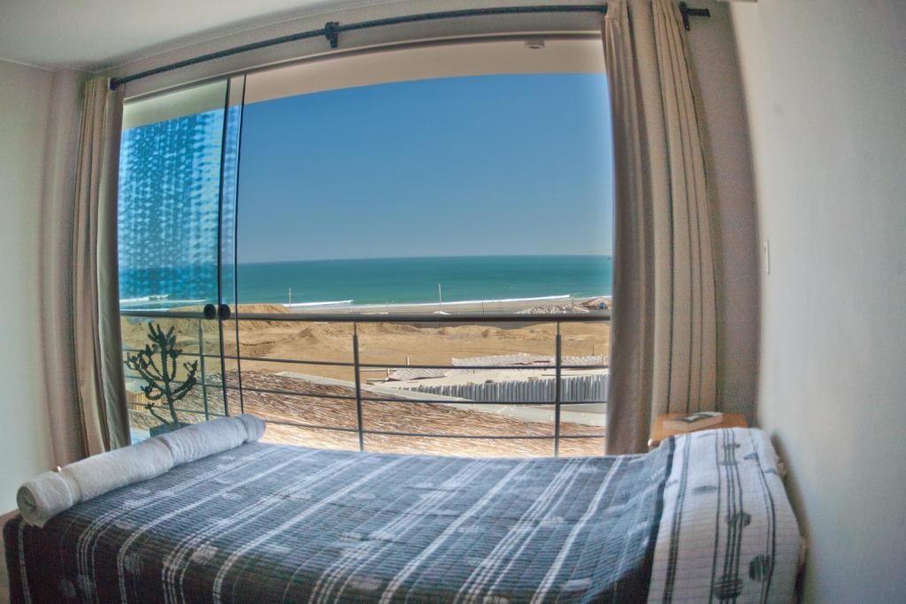 una camera da letto con finestra affacciata sulla spiaggia di El Hueco Villas a Lobitos