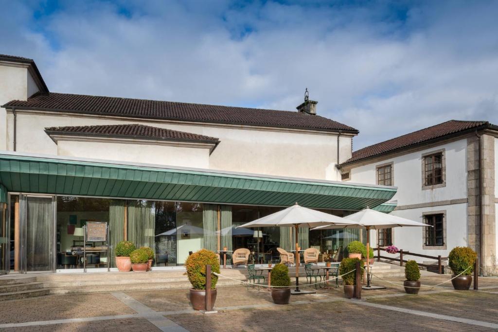um edifício com mesas e guarda-chuvas à sua frente em Hotel Palacio del Carmen, Autograph Collection em Santiago de Compostela
