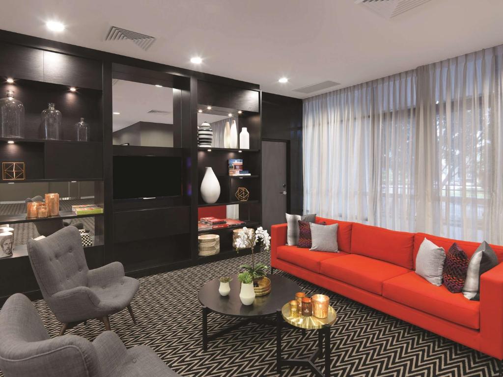 a living room with a red couch and two chairs at Adina Apartment Hotel Sydney Airport in Sydney