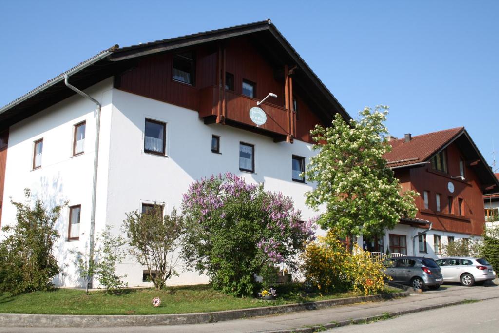 ein weißes Gebäude mit braunem Dach in der Unterkunft Abendruhe Hotel - kontaktloser Check In in Oberhaching