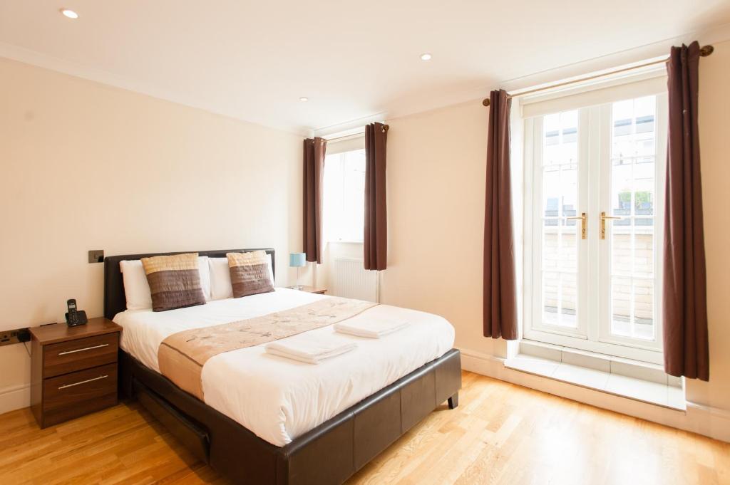 ein Schlafzimmer mit einem Bett und einem großen Fenster in der Unterkunft London Serviced Apartments in London
